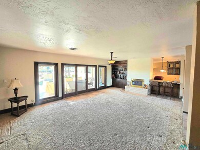 Living area with a textured ceiling, light colored carpet, and a brick fireplace