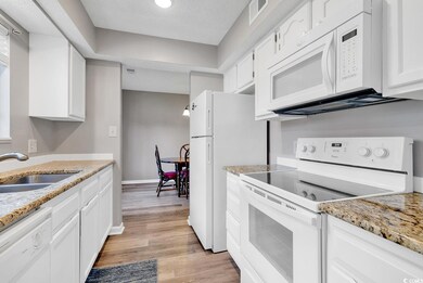 Kitchen with sink, white appliances, light hardwood / wood-style flooring, white cabinetry, and a textured ceiling