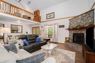 Living room featuring a stone fireplace, high vaul