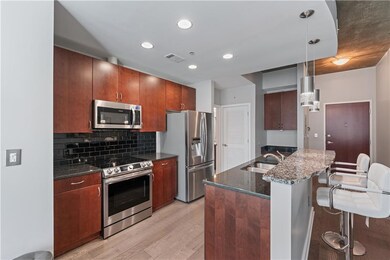 Kitchen with appliances with stainless steel finishes, dark stone countertops, decorative light fixtures, a breakfast bar area, and recessed lighting