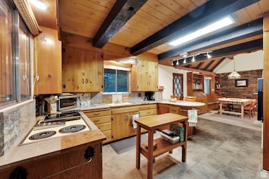 Kitchen featuring light countertops, wood ceiling, white electric cooktop, backsplash, and a peninsula