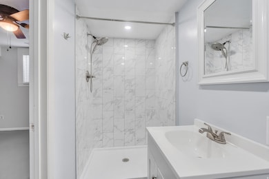 Full bath featuring vanity, a shower stall, and ceiling fan