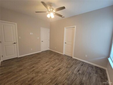 Unfurnished room with dark wood-type flooring, visible vents, baseboards, and a ceiling fan