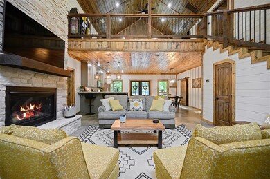 Living room featuring wooden walls, a stone firepl
