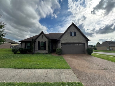 French country home featuring brick siding, driveway, a front lawn, and an attached garage
