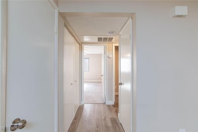 Corridor with light wood-style floors, a textured