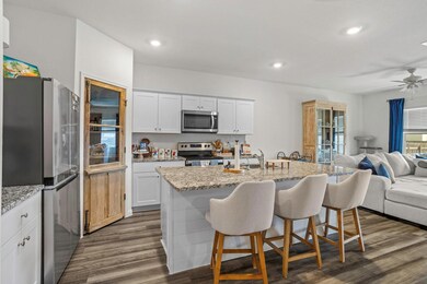 Kitchen featuring stainless steel appliances, open floor plan, a breakfast bar, dark wood-type flooring, and a sink