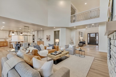 Living area with recessed lighting, light wood-style flooring, a chandelier, and a high ceiling