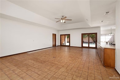 Spare room featuring a raised ceiling, light tile patterned flooring, a chandelier, and ceiling fan