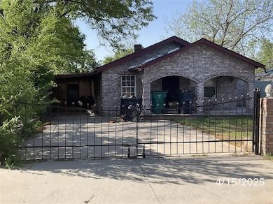 View of front of property featuring brick siding, a fenced front yard, concrete driveway, and a gate