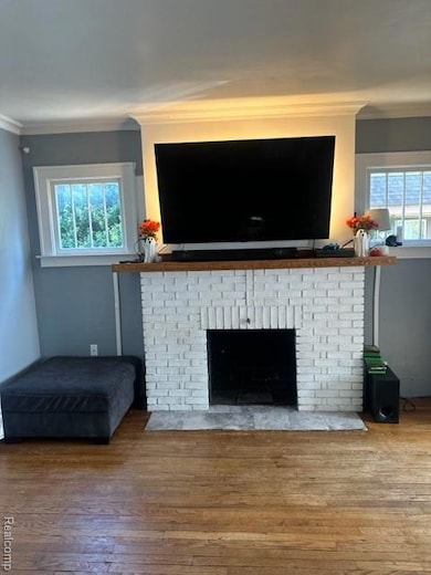 Living area featuring crown molding, hardwood / wood-style floors, and a brick fireplace