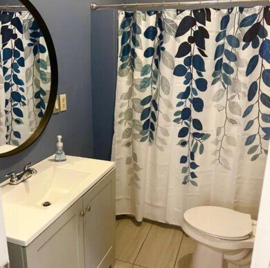 Bathroom with vanity, toilet, tile patterned floors, and a shower with shower curtain