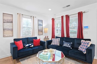 Living area featuring healthy amount of natural light, wood finished floors, baseboards, and recessed lighting