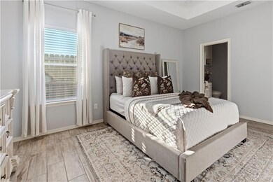 Bedroom featuring light wood-style floors, baseboards, and ensuite bathroom