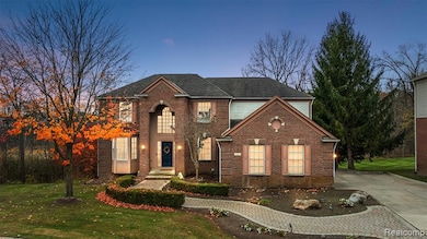 Traditional home with a lawn, brick siding, concrete driveway, and a shingled roof