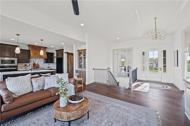 Living room with dark wood-style flooring, recessed lighting, ceiling fan, and a chandelier