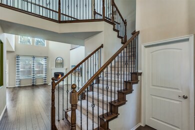 Staircase featuring a high ceiling, a warm lit fireplace, and hardwood / wood-style flooring
