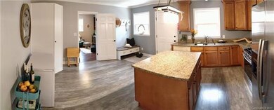 Kitchen has custom cabinets, granite counter tops, laminate wood flooring, and huge Lazy Susan pantry cabinet to the left of the living room door. Large Island has cabinets on both sides providing plenty of storage space. Rear entrance to kitchen wit