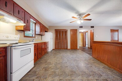 Kitchen featuring white appliances, a ceiling fan, under cabinet range hood, a textured ceiling, and light countertops