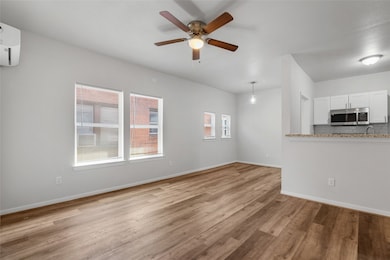 This spacious living room features sleek luxury vinyl plank flooring, providing both durability and style. The open-concept design allows for flexible furniture arrangements and offers easy access to the adjacent kitchen. A ceiling fan enhances comfort, while large windows fill the room with natural light, creating a bright and airy atmosphere. The neutral color palette throughout the space offers a modern, clean look, making it a perfect canvas for personalized decor.