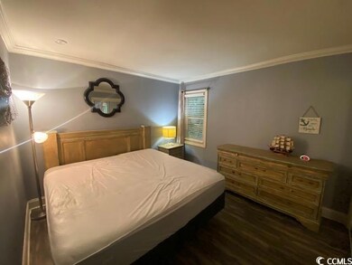 Bedroom featuring wood-style flooring and crown mo