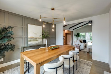 Dining area with dark wood-style flooring, vaulte