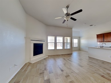 Unfurnished living room with wood tiled floors, a fireplace with raised hearth, and a ceiling fan