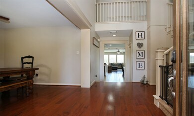Two story foyer with lots of light , hardwood floors and an open staircase.