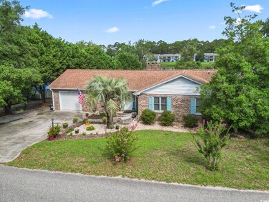 Single story home with brick siding, a garage, a front yard, and concrete driveway