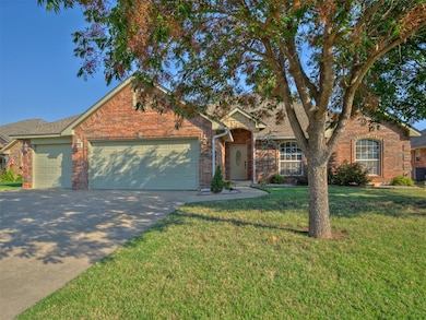 Ranch-style home featuring driveway, a front lawn, a garage, and brick siding
