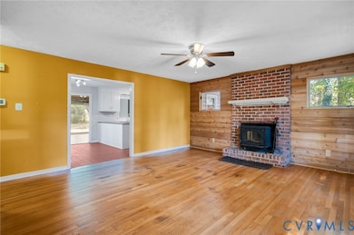 Unfurnished living room featuring wooden walls, plenty of natural light, hardwood / wood-style flooring, a textured ceiling, and ceiling fan