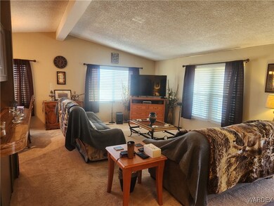 Carpeted living room with vaulted ceiling with bea