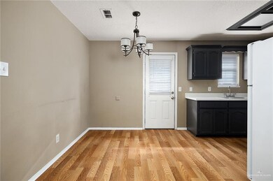 Kitchen with a wealth of natural light, sink, light hardwood / wood-style flooring, a notable chandelier, and white fridge