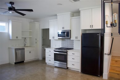 Kitchen with stainless steel appliances, open shelves, white cabinetry, decorative backsplash, and a ceiling fan