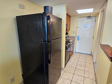 Kitchen featuring black appliances, brown cabinetry, and light tile patterned floors