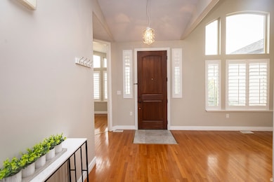 Entrance foyer featuring light wood-style floors, vaulted ceiling, and an AC wall unit