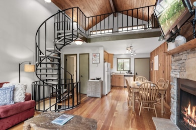 Living area featuring high vaulted ceiling, a fireplace, light wood-style flooring, stairs, and wooden walls