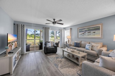 Living room featuring a textured ceiling, ceiling fan, and wood finished floors