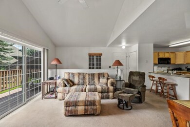 Carpeted living room featuring vaulted ceiling, si