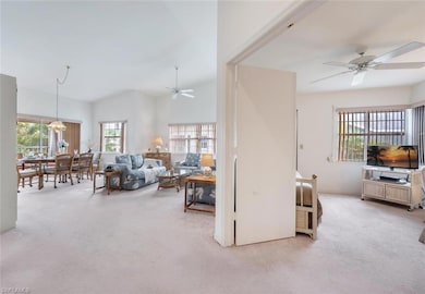Living area featuring plenty of natural light, ceiling fan, carpet flooring, and vaulted ceiling