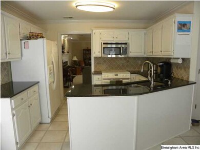 Kitchen with lots of cabinets, granite, tile backs