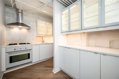 Kitchen features glass cabinets plenty of storage with hidden microwave