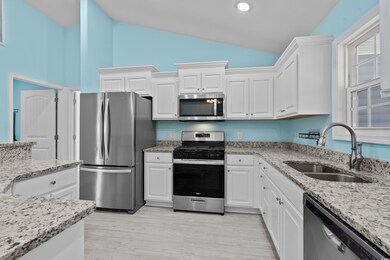 Kitchen with white cabinetry, sink, appliances wit