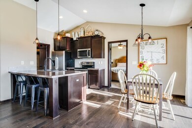 Kitchen with lofted ceiling, tasteful backsplash, a kitchen breakfast bar, dark brown cabinets, and appliances with stainless steel finishes