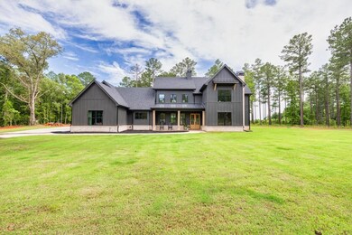 Rear view of house with a chimney, a yard, a shingled roof, board and batten siding, and a patio