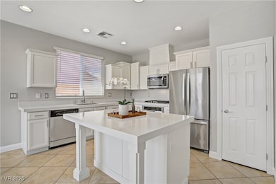 Kitchen featuring stainless steel appliances, white cabinets, a center island, light tile patterned floors, and recessed lighting