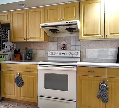 Kitchen with decorative backsplash, white range with electric cooktop, and light tile patterned floors