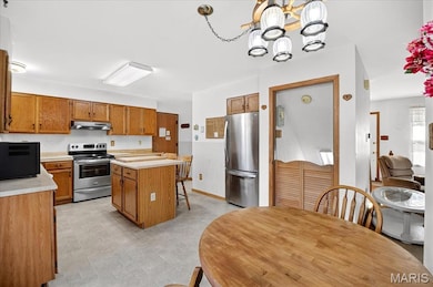 Kitchen featuring stainless steel appliances, light countertops, a chandelier, and a kitchen island