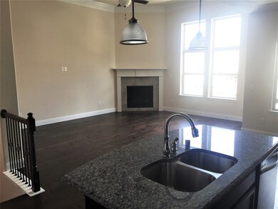 Kitchen with dark wood finished floors, dark stone counters, dishwasher, a fireplace, and open floor plan