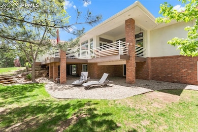 Rear view of house with a patio area, a balcony, brick siding, a lawn, and stucco siding